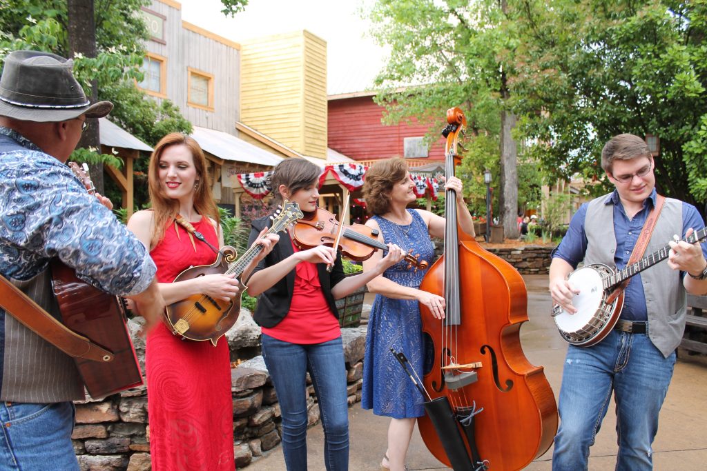 A youth bluegrass band is playing outside at Silver Dollar City.