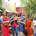 A youth bluegrass band is playing outside at Silver Dollar City.
