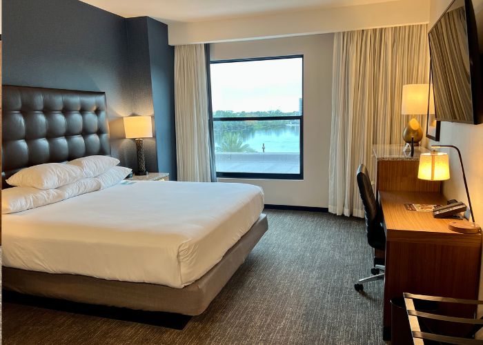 Bedroom at Drury Inn with a large window offering views of the pool and Disney Springs.